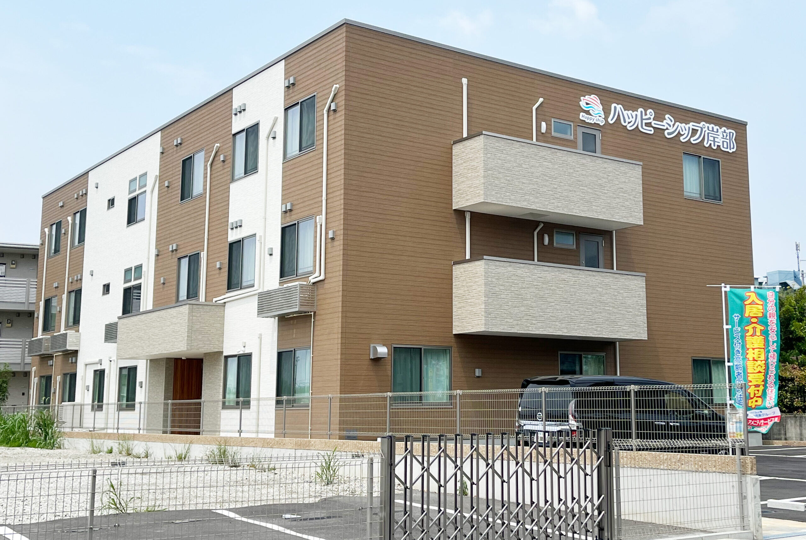 介護施設の建物外観。3階建てのモダンな外観で、サイン看板が見える。